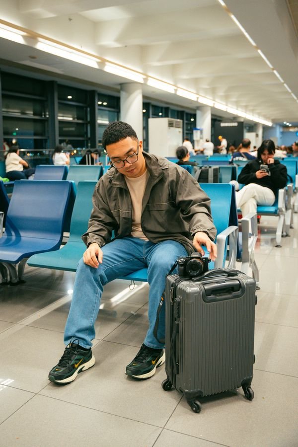 A traveler waiting with luggage in an international airport terminal